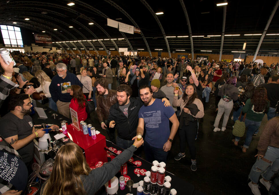 Austin Jacobs, front center right, receives a glass of beer next to friend, Aaron Burns, both of San Jose, at the Old Caz Beer line during the 26th Annual Battle of the Brews, at the Sonoma County Fairgrounds, Saturday, April 1, 2023, in Santa Rosa. (Darryl Bush / For The Press Democrat)